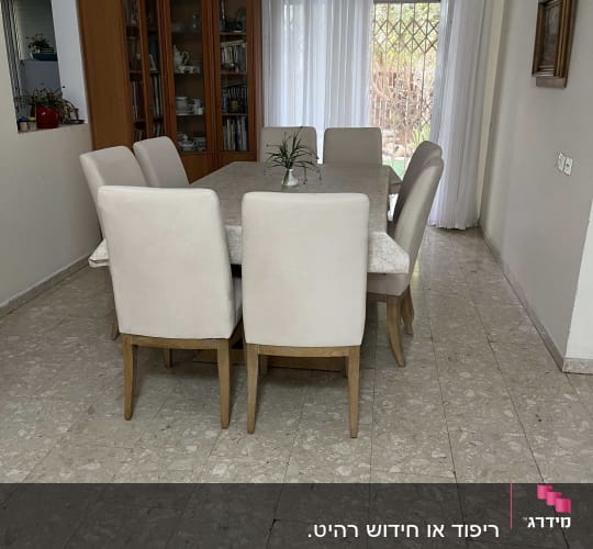כיסאות מרופדים סביב שולחן אוכל בחדר אוכל מואר